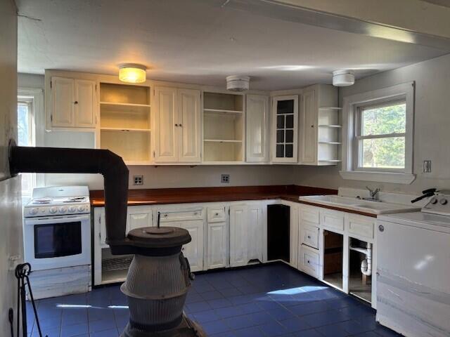 kitchen with dark tile patterned floors, open shelves, washer / clothes dryer, and gas range gas stove