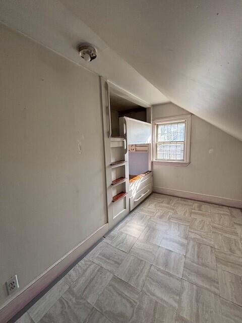 additional living space with baseboards and vaulted ceiling