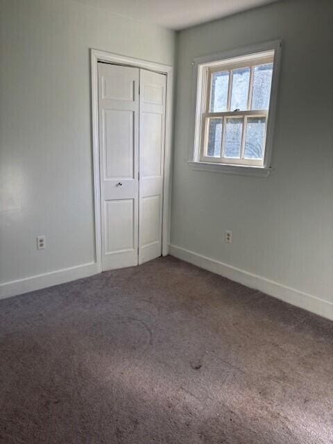 unfurnished bedroom featuring carpet flooring, baseboards, and a closet