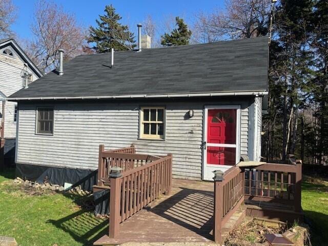 rear view of house with a shingled roof, a yard, and a deck
