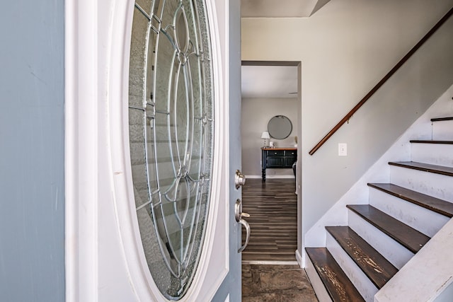 foyer entrance with stairs and baseboards