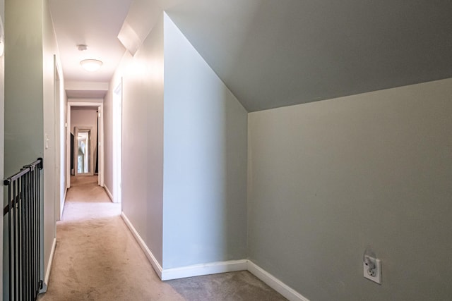 corridor featuring light colored carpet and baseboards