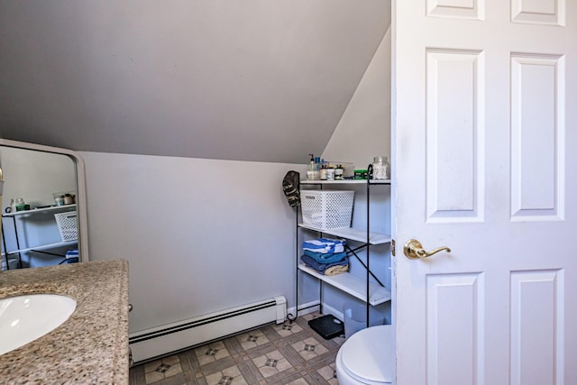 bathroom with a baseboard heating unit, vaulted ceiling, toilet, tile patterned floors, and vanity