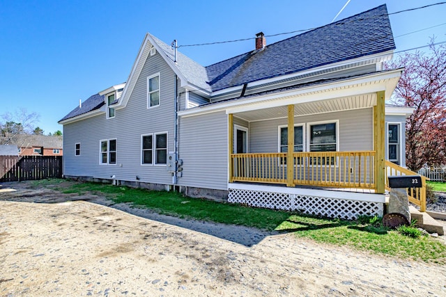 back of property featuring covered porch, fence, and a shingled roof