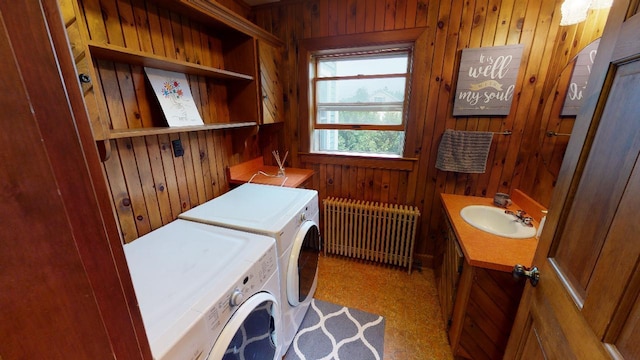 laundry room featuring radiator, wooden walls, a sink, and independent washer and dryer