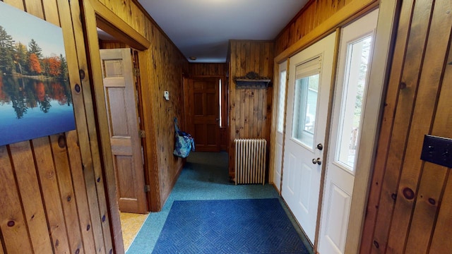hall with radiator heating unit, wooden walls, and carpet floors