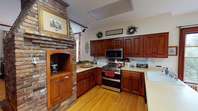 kitchen featuring stainless steel appliances, light countertops, light wood-style flooring, and a sink