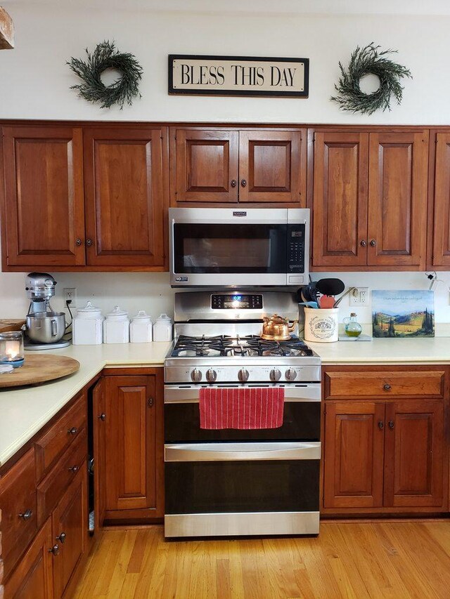 kitchen featuring appliances with stainless steel finishes, light countertops, and brown cabinetry
