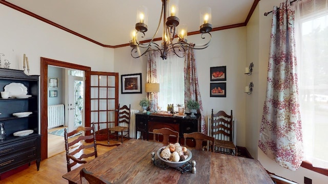 dining area featuring crown molding, an inviting chandelier, radiator heating unit, and wood finished floors