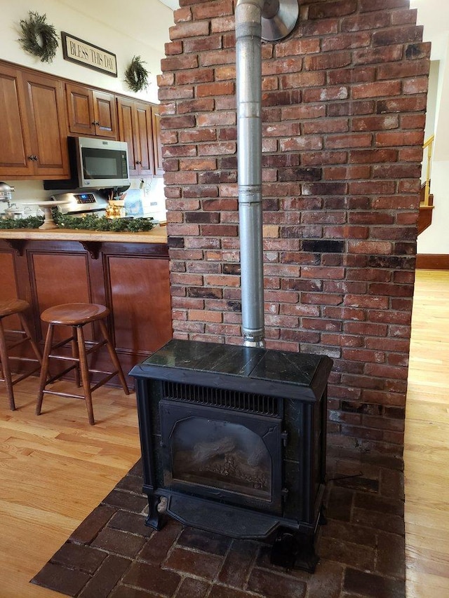 room details with stainless steel microwave, a wood stove, and wood finished floors