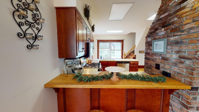 kitchen with a sink, a kitchen breakfast bar, a peninsula, light countertops, and dishwasher