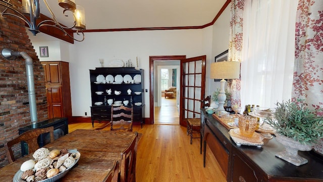 dining area with crown molding, a wood stove, french doors, and light wood-style floors