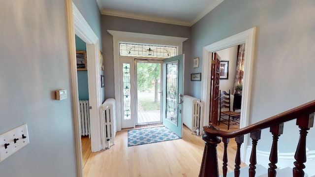 entrance foyer with radiator, light wood-style floors, and ornamental molding
