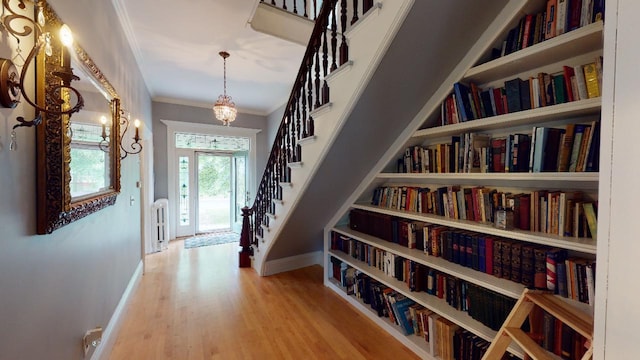 corridor with crown molding, stairway, wood finished floors, and baseboards
