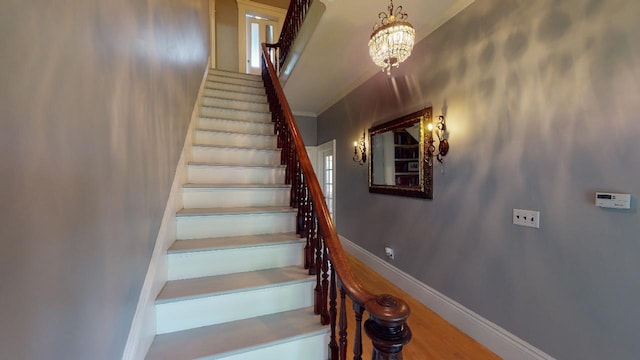 stairway featuring an inviting chandelier, crown molding, and baseboards