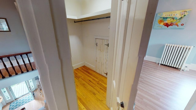 interior space with baseboards, radiator, and wood finished floors