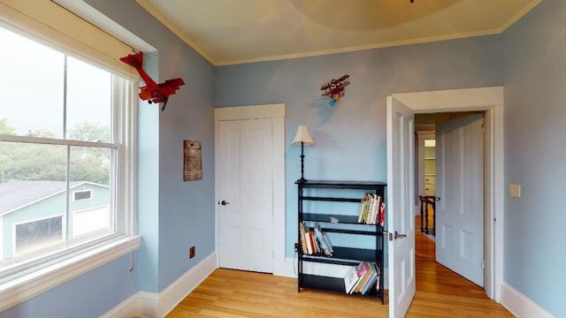 bedroom featuring ornamental molding, multiple windows, and light wood-style flooring