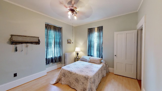 bedroom with radiator heating unit, ornamental molding, light wood-style flooring, and baseboards