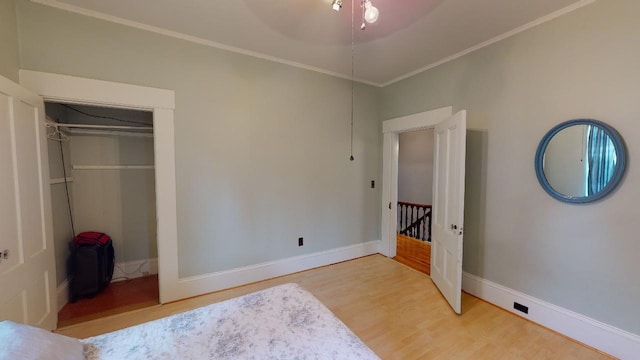 bedroom with crown molding, a closet, wood finished floors, and baseboards