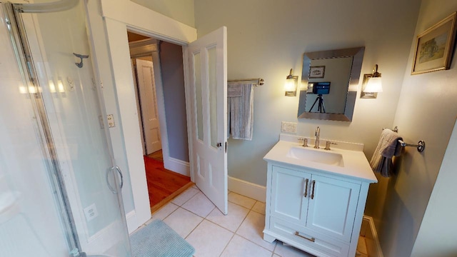 full bath featuring baseboards, a shower with door, tile patterned flooring, and vanity