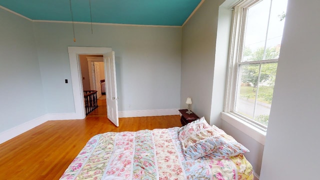 bedroom featuring wood finished floors, ornamental molding, and baseboards