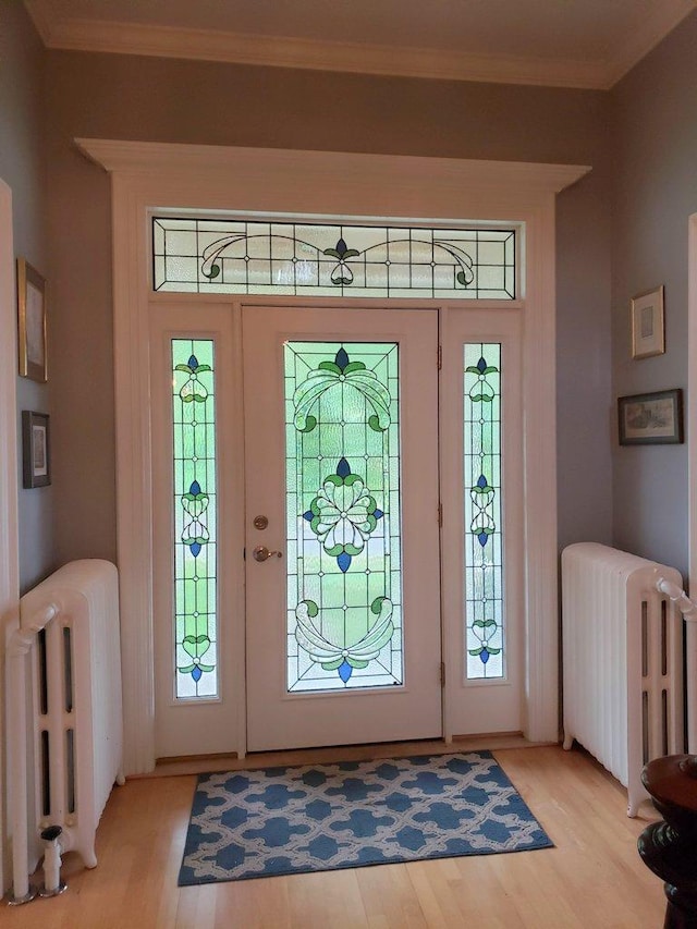foyer featuring radiator, ornamental molding, and light wood finished floors