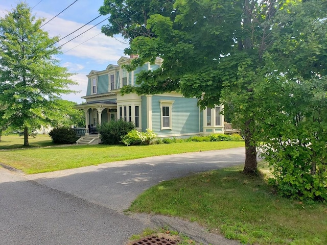 italianate home with driveway, covered porch, and a front lawn