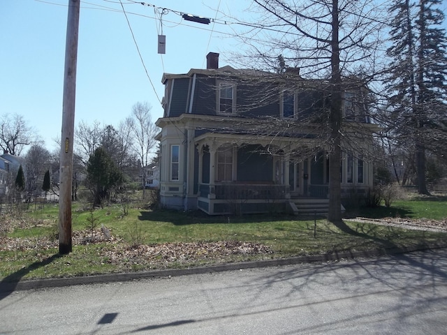 view of front of house with a front lawn, covered porch, and a chimney