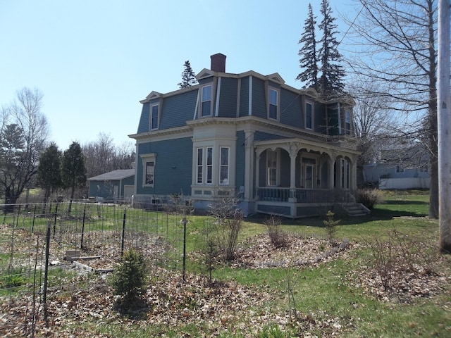 exterior space with a chimney, a porch, a yard, and mansard roof