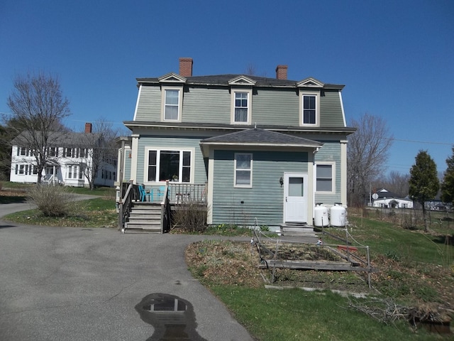 exterior space with a chimney, covered porch, a garden, and roof with shingles