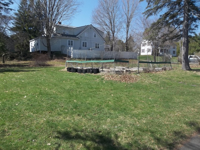 view of yard featuring a trampoline and fence