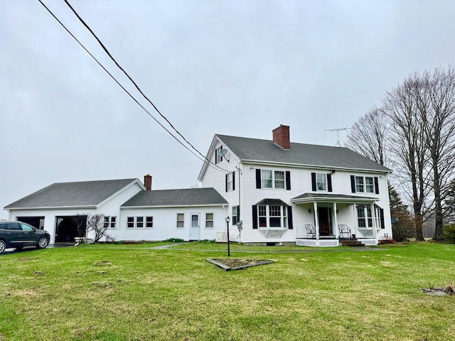 view of front facade with a chimney, a porch, a front yard, and an attached garage