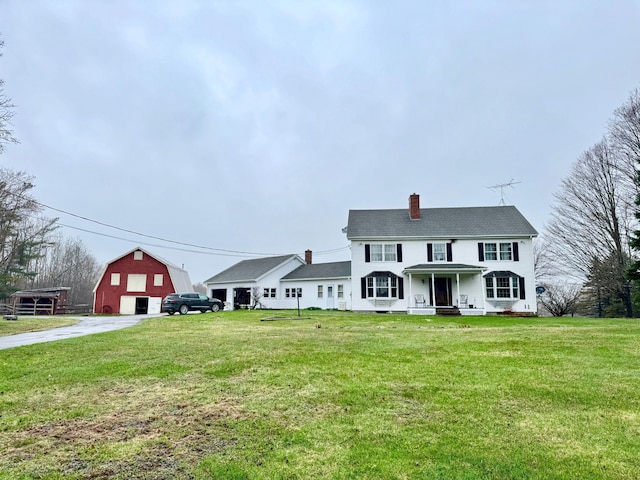 view of front of property with a chimney, a barn, an outbuilding, a detached garage, and a front lawn