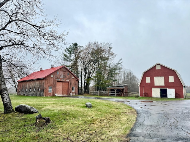 view of yard featuring fence, an outdoor structure, a barn, and a garage