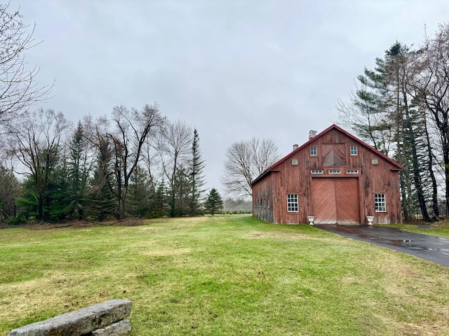 view of yard with an outbuilding, a garage, a barn, and aphalt driveway
