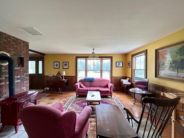 living area featuring visible vents, plenty of natural light, and a wainscoted wall