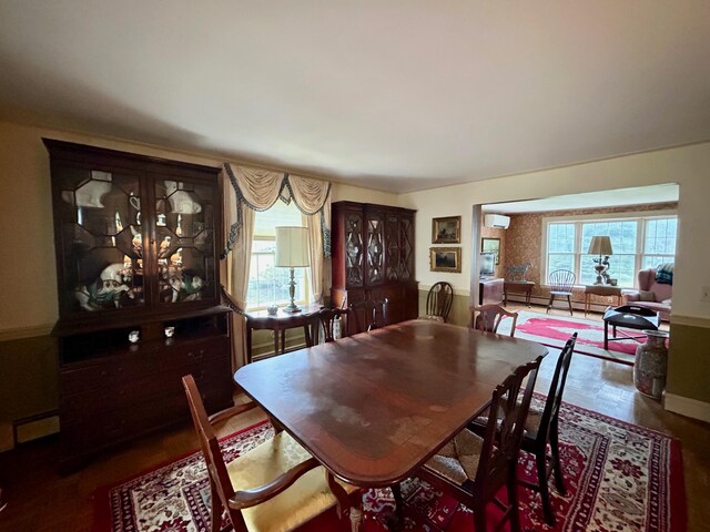 dining area with a wall unit AC and wood finished floors