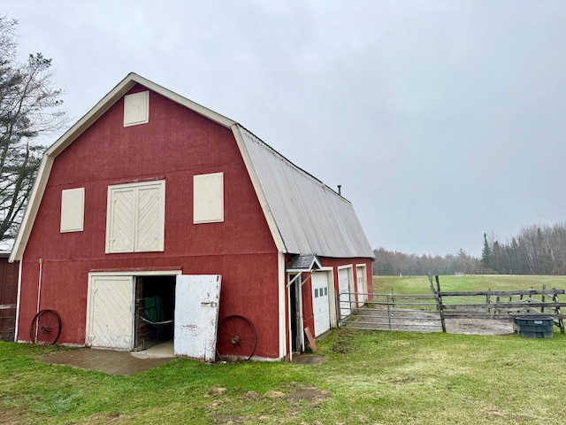 view of barn with fence and a yard
