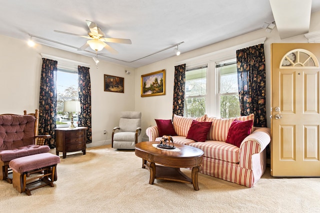 living area featuring rail lighting, plenty of natural light, a ceiling fan, and light colored carpet
