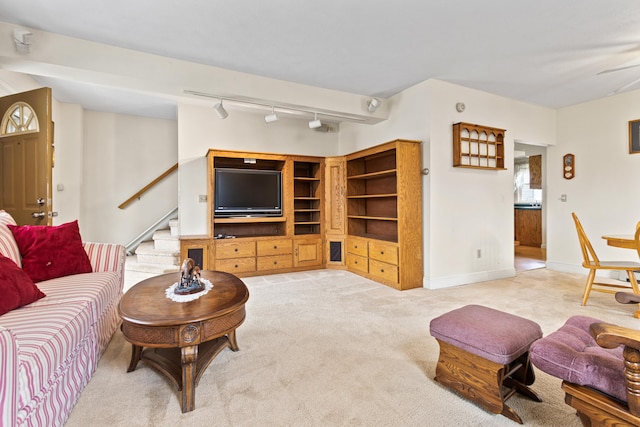 living room with a ceiling fan, track lighting, stairway, baseboards, and light colored carpet