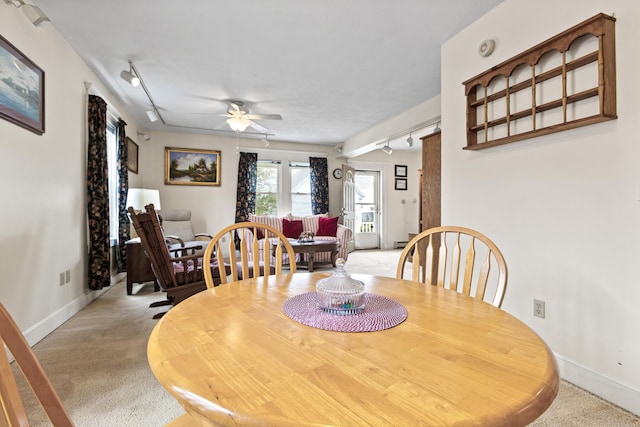 dining area featuring rail lighting, light carpet, baseboards, and ceiling fan
