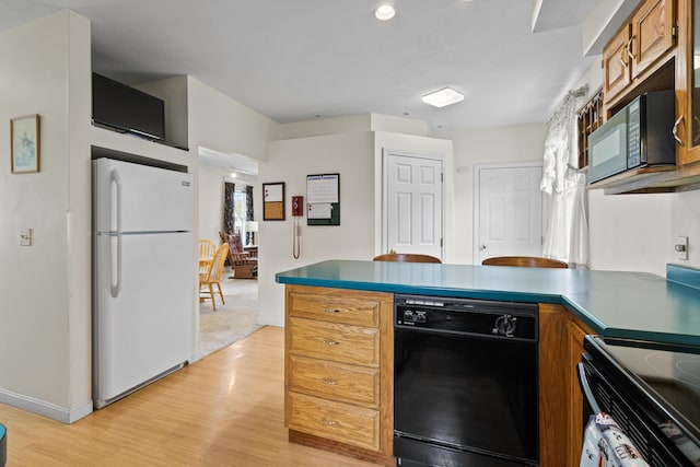 kitchen featuring a peninsula, light wood-style floors, baseboards, and black appliances