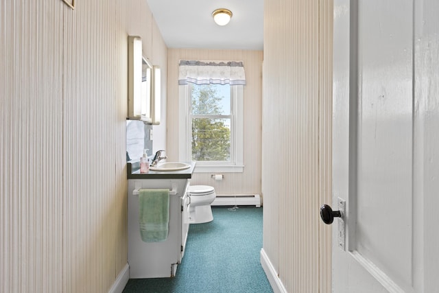 half bathroom featuring toilet, baseboards, baseboard heating, and vanity