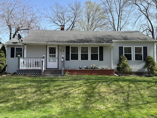 ranch-style home featuring a front lawn, roof with shingles, covered porch, and a chimney