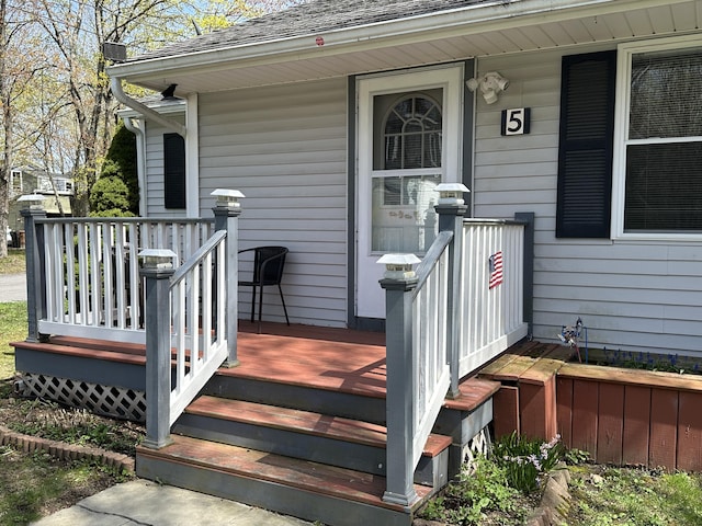 doorway to property with a wooden deck and a shingled roof