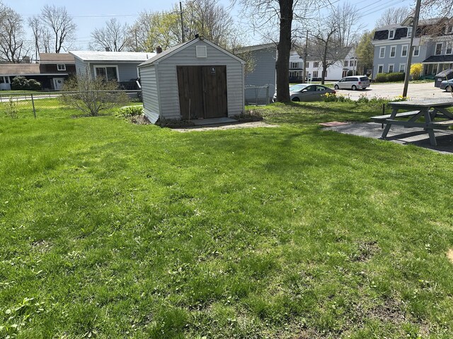 view of yard featuring fence, a residential view, an outdoor structure, and a storage unit