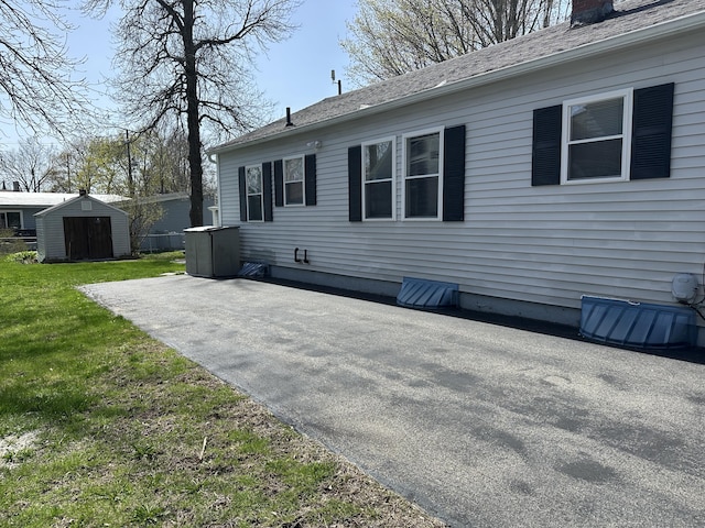 back of house with a chimney, a storage shed, a lawn, an outbuilding, and a patio