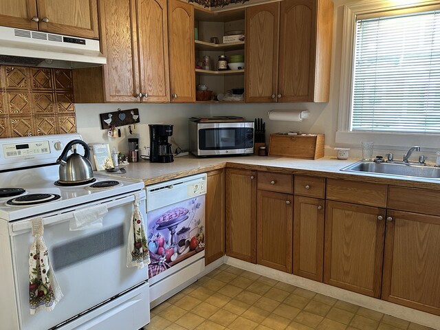 kitchen with white appliances, light countertops, under cabinet range hood, brown cabinets, and a sink