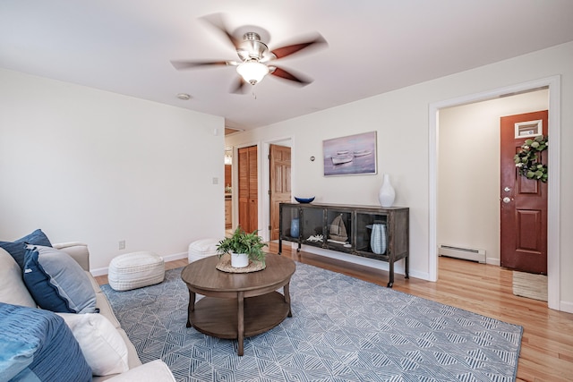 living area with light wood-style floors, a baseboard radiator, baseboards, and a ceiling fan
