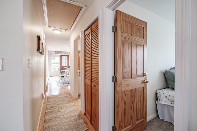 hallway featuring baseboards and attic access